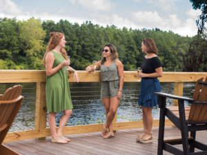 three women standing on the deck holding a beverage